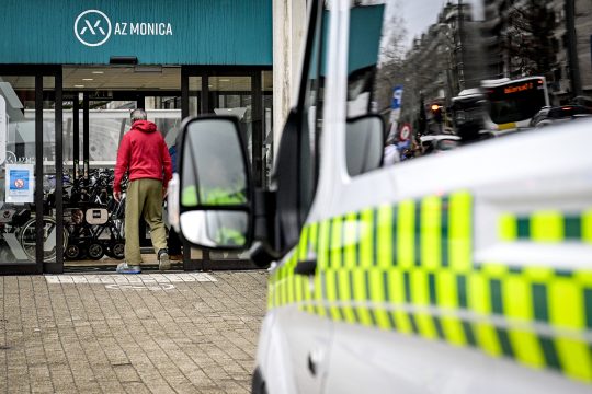 Eingangsbereich der Klinik, ein Mann geht durch die Tür. Im Vordergrund ein Ambulanzfahrzeug