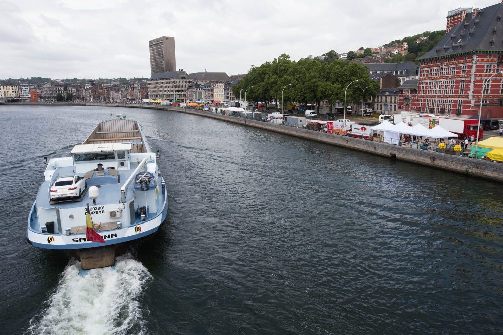 Marktstände entlang des Ufers beim Sonntagsmarkt "La Batte" in Lüttich, davor die Maas, auf der ein Schiff fährt