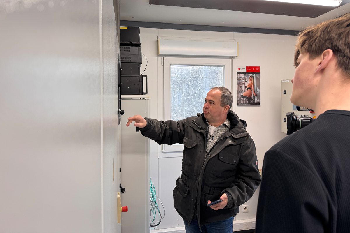 Betriebsleiter Alwin Lenges steht an einem Schaltschrank und erklärt etwas