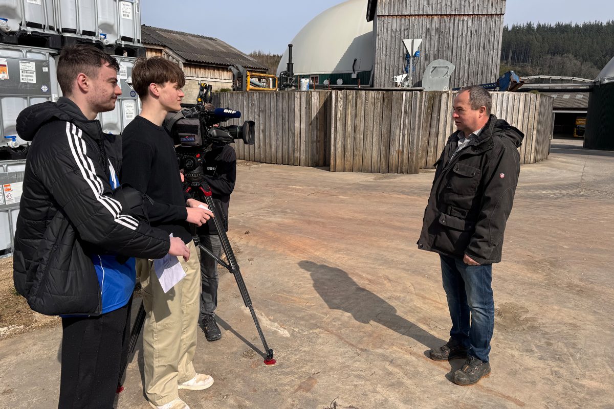 Maxime und Jonathan von der BS, zusammen mit Betriebsleiter Alwin Lenges auf dem Firmengelände, eine BRF-Kamera ist für ein Interview aufgestellt worden