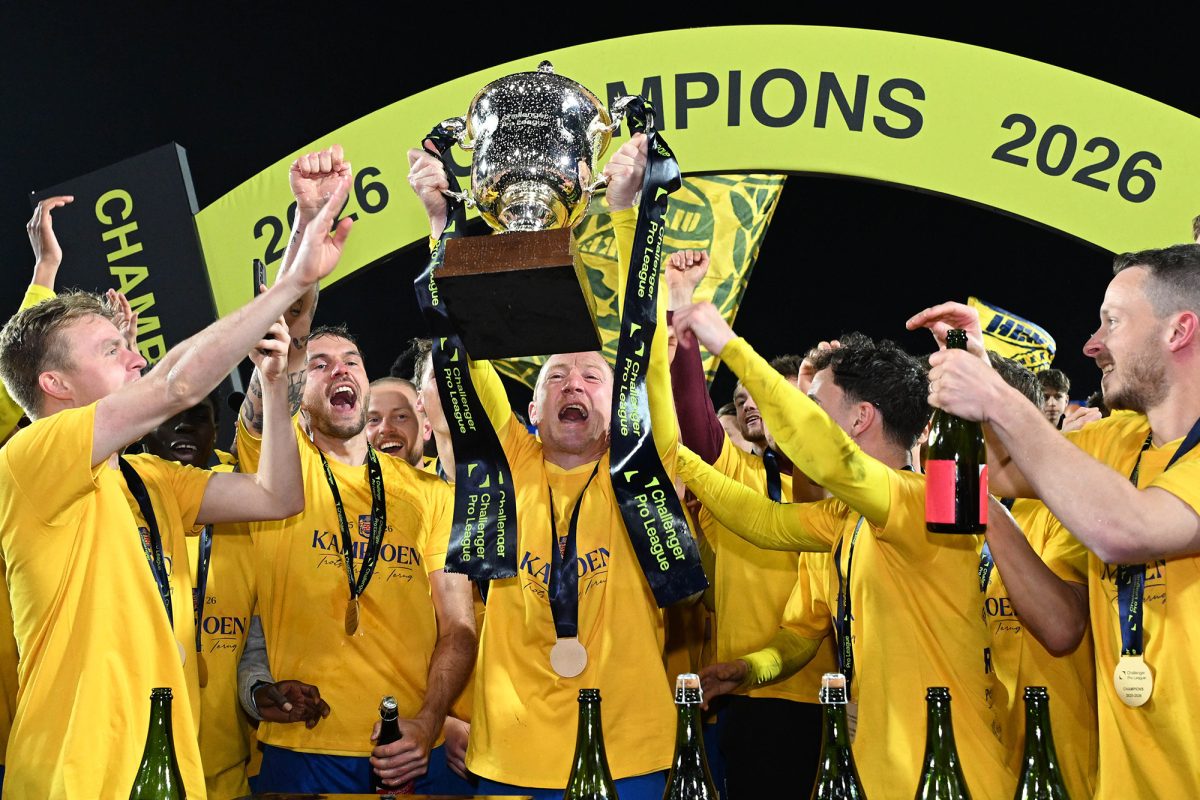 Christian Brüls reckt den Pokal in die Höhe und schreit vor Freude, um ihn herum stehen seine Mannschaftskollegen und jubeln mit