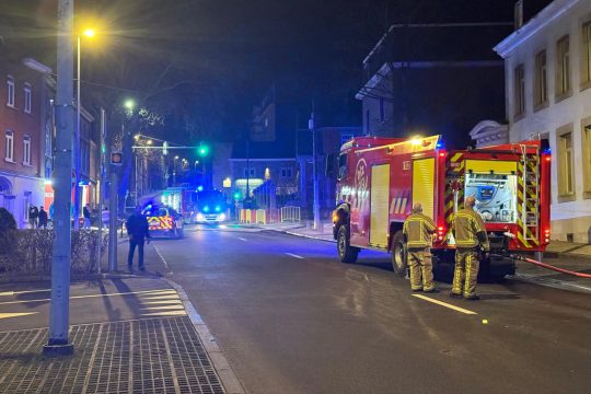 Feuerwehrleute und Einsatzfahrzeuge mit Blaulicht stehen in der Straße