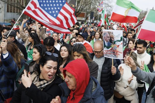 Demonstranten schwenken Flaggen des Iran und der USA
