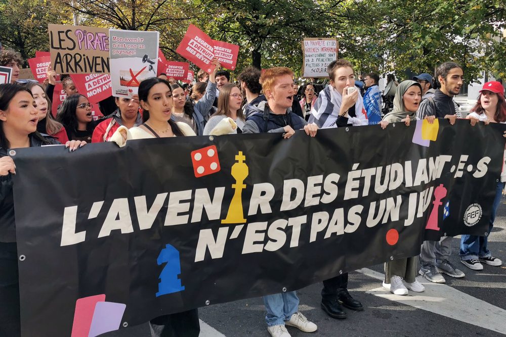 Studenten tragen ein großes Banner mit der Aufschrift "Die Zukunft der Studenten ist kein Kinderspiel" durch die Straßen