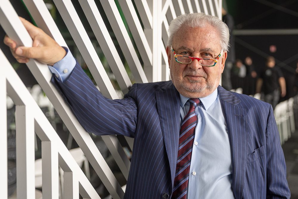 Der CEO von Katoen Natie, Fernand Huts, posiert für ein Foto, mit einer Hand hält er eine Strebe an einer Art dekorativer Sprossenwand