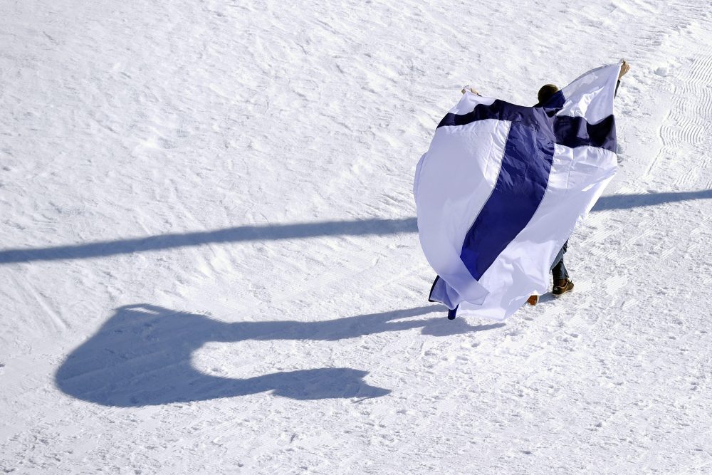 Mann mit finnischer Flagge im Schnee