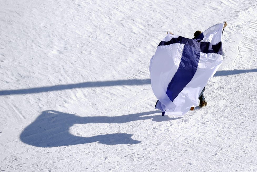 Mann mit finnischer Flagge im Schnee