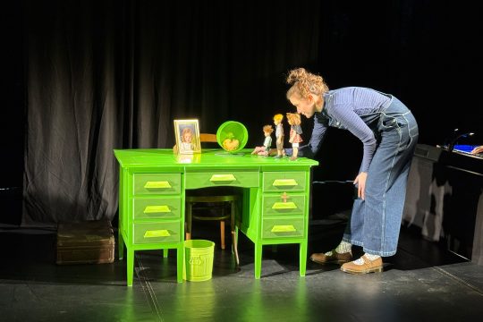 Schauspielerin Marie Dolders spielt das Theaterstück an einem leuchtend grünen Tisch