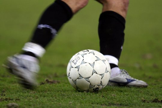 Nahaufnahme der Beine eines Fußballspielers mit Ball auf dem Platz