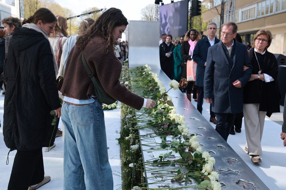 Junge Frau legt eine weiße Rose nieder bei der Gedenkfeier für die Opfer der Terroranschläge 2016 am 22. März 2026