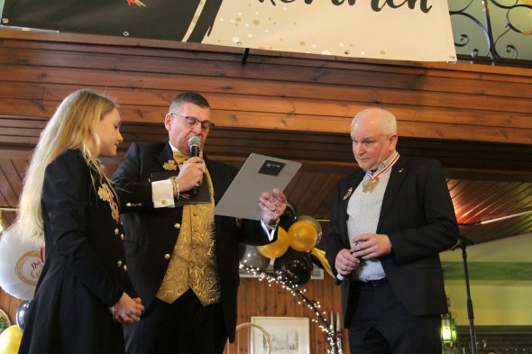 Patrick Wertz übergibt Pastor Peter Dries den Preis "Dat jölde Hatz"