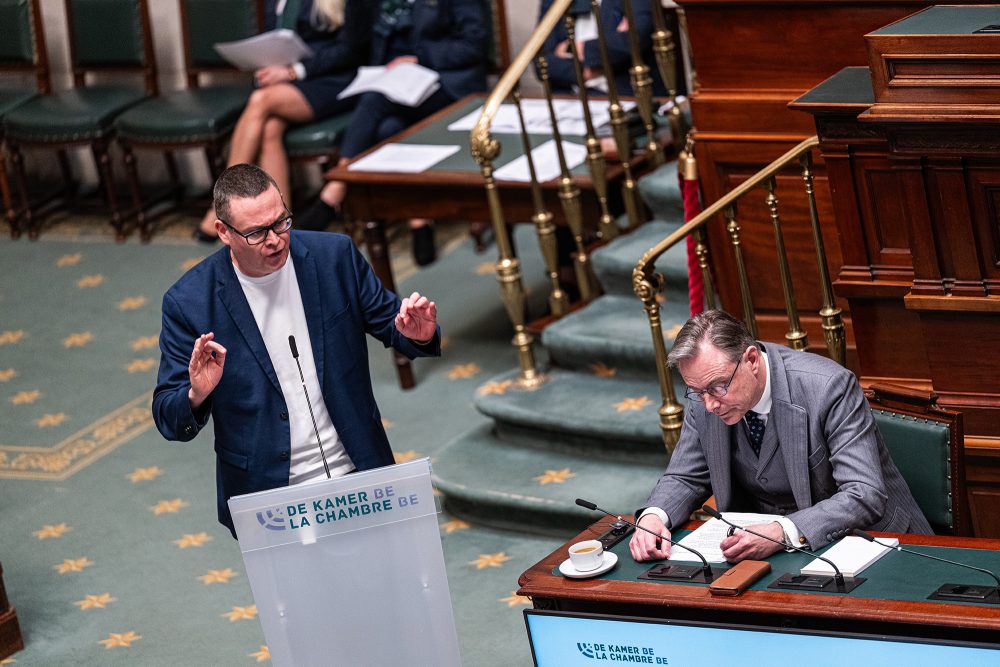 Raoul Hedebouw von der PTB steht am Rednerpult, Bart de Wever nimmt Notizen