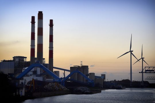 Schornsteine und Türme des ehemaligen Kraftwerks, dahinter Windräder