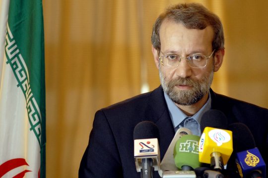 Ali Laridschani, vor ihm auf einem Tisch stehen mehrere Mikrofone