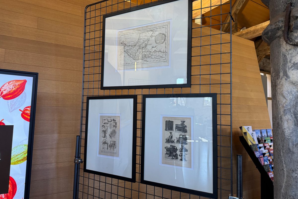Drei Bilder mit Zeichnungen zur historischen Schokoladenherstellung hängen im Tourismusbüro Lüttich