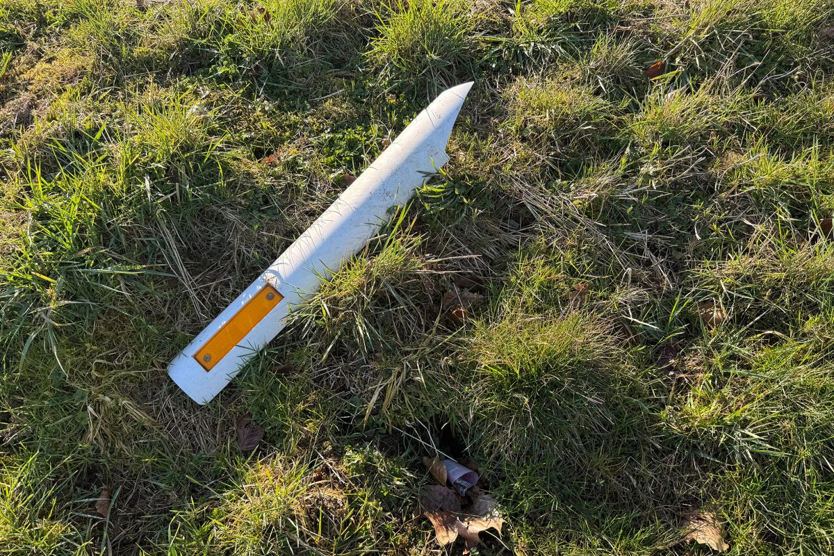 Ein kaputter Straßenpfosten liegt im Gras