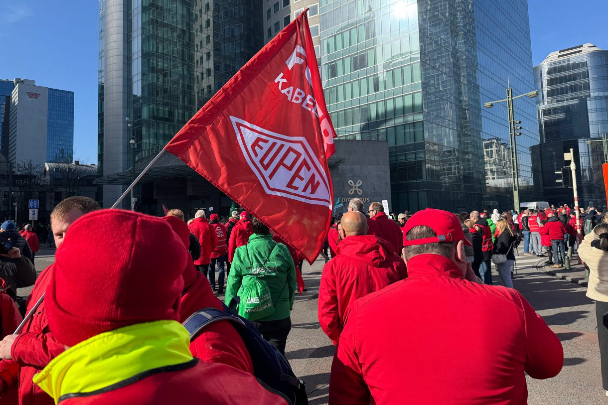 Gewerkschaftsmitglieder versammeln sich auf zentralem Platz in Brüssel, auch eine Gewerkschaftsflagge von Mitarbeitern des Kabelwerk Eupen ist zu sehen