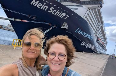 Caroline Frisque steht mit einer weiteren Frau vor einem Kreuzfahrtschiff
