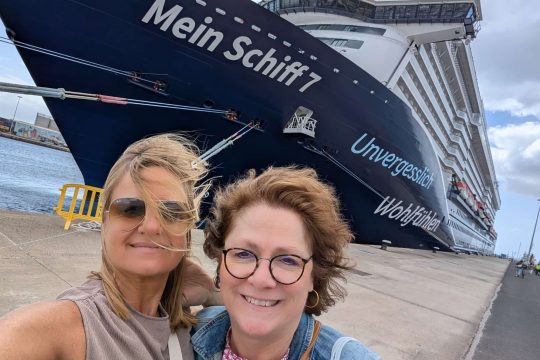 Caroline Frisque steht mit einer weiteren Frau vor einem Kreuzfahrtschiff