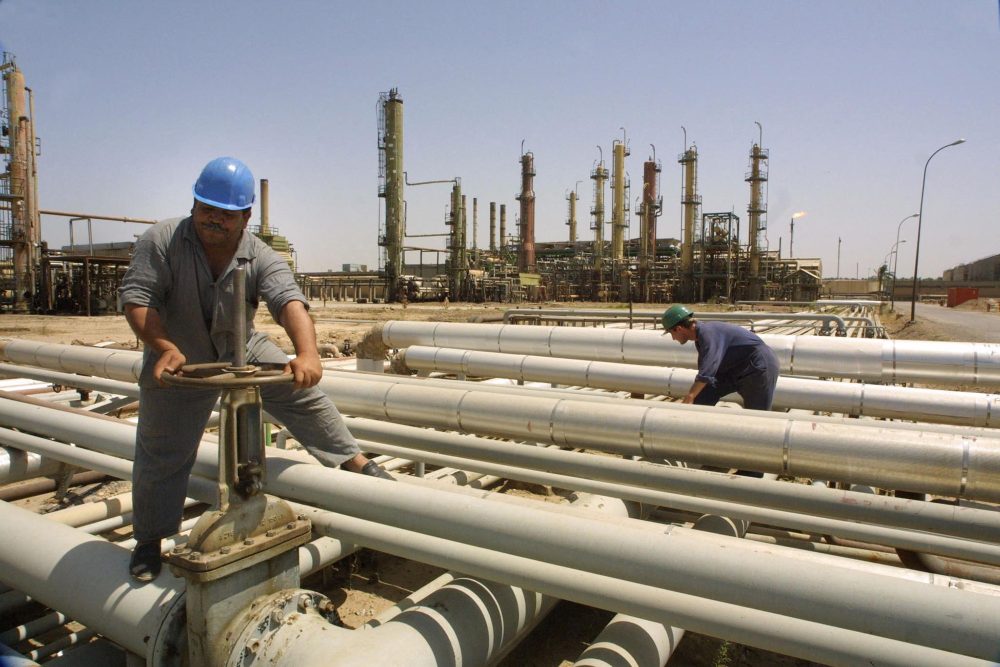 Zwei Arbeiter an Leitungen einer Ölraffinerie im Irak