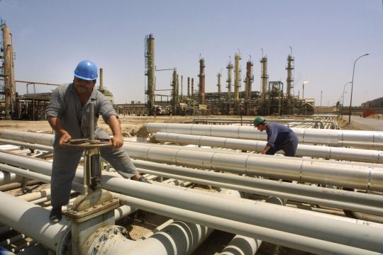 Zwei Arbeiter an Leitungen einer Ölraffinerie im Irak
