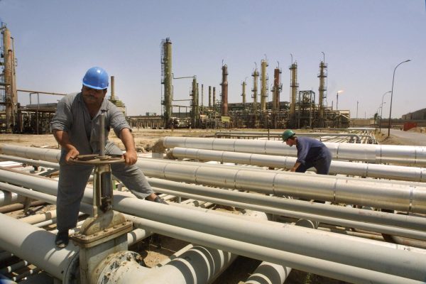 Zwei Arbeiter an Leitungen einer Ölraffinerie im Irak