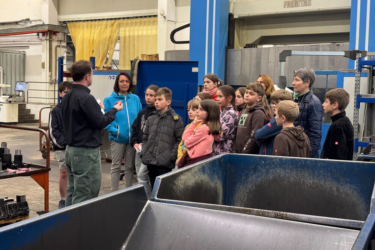 Die Kinder lassen sich in der Produktionshalle mit diversenen Maschinen von Mitarbeitern etwas erklären