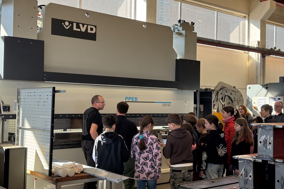 Die Kinder lassen sich in der Produktionshalle mit diversenen Maschinen von Mitarbeitern etwas erklären