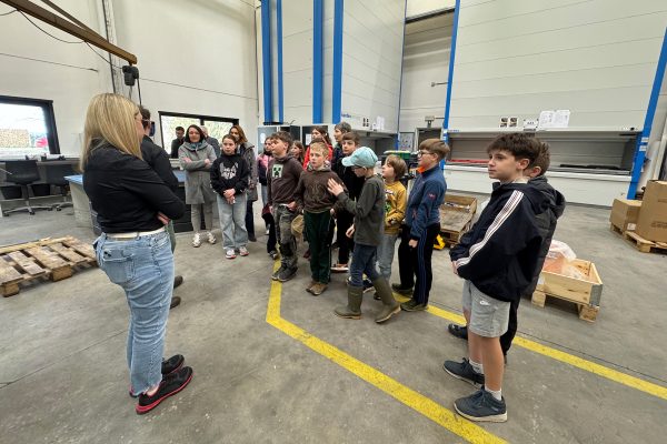 Die Kinder lassen sich in der Produktionshalle mit diversenen Maschinen von Mitarbeitern etwas erklären