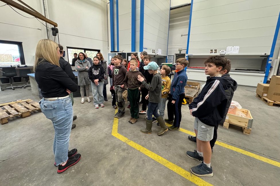 Die Kinder lassen sich in der Produktionshalle mit diversenen Maschinen von Mitarbeitern etwas erklären