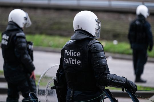 Drei Polizisten in Schutzmontur mit Helm und Schutzschild