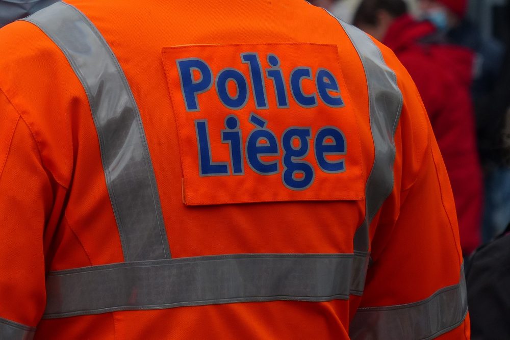 Polizist in oranger Jacke mit der Aufschrift "Police Liège"
