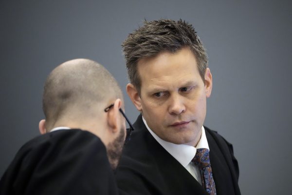 Staatsanwalt Sturla Henriksboe neben einer weiteren Person, die ihm gerade etwas sagt