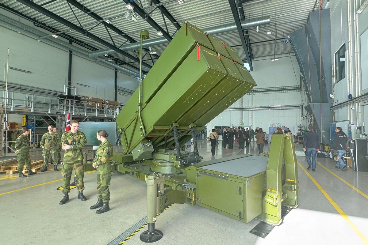 Frauen und Männer in Militäruniform stehe neben grün gestrichenen militärischen Gerätschaften