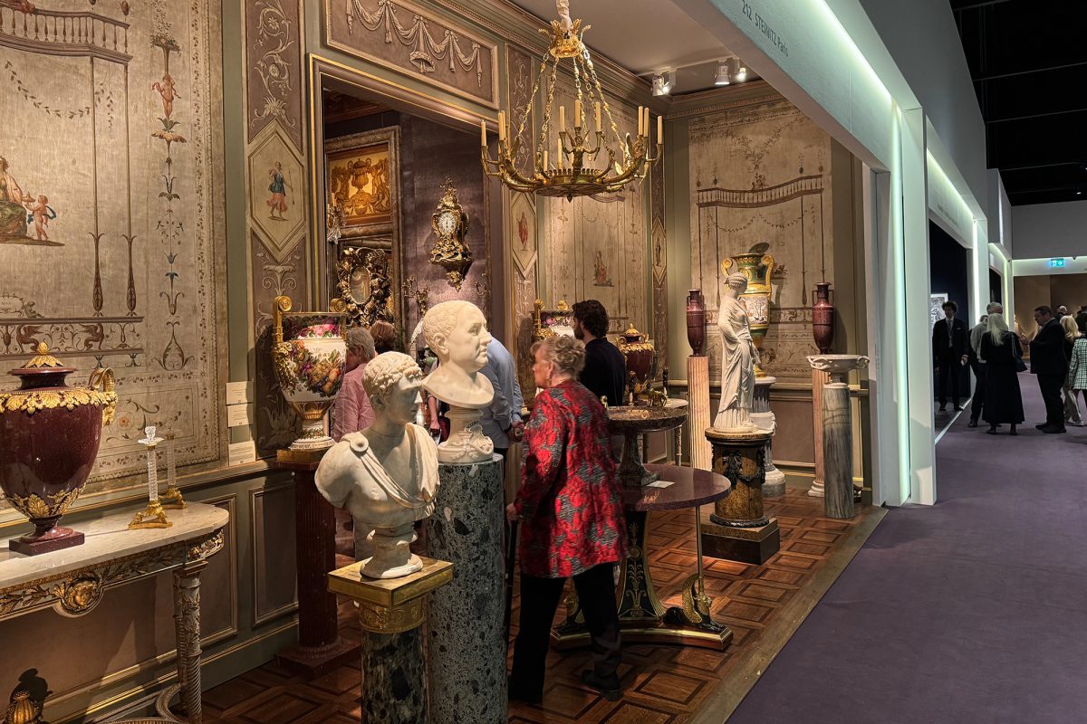 Stand eines Ausstellers mit unter anderem antik erscheinenden Büsten, Vasen und Wandmalereien - eine Besucherin schaut sich etwas an