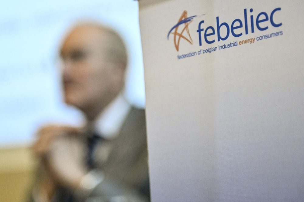 Das Logo des Verbandes auf einem Banner, dahinter ist schemenhaft die Silhouette eines Mannes im Anzug zu sehen