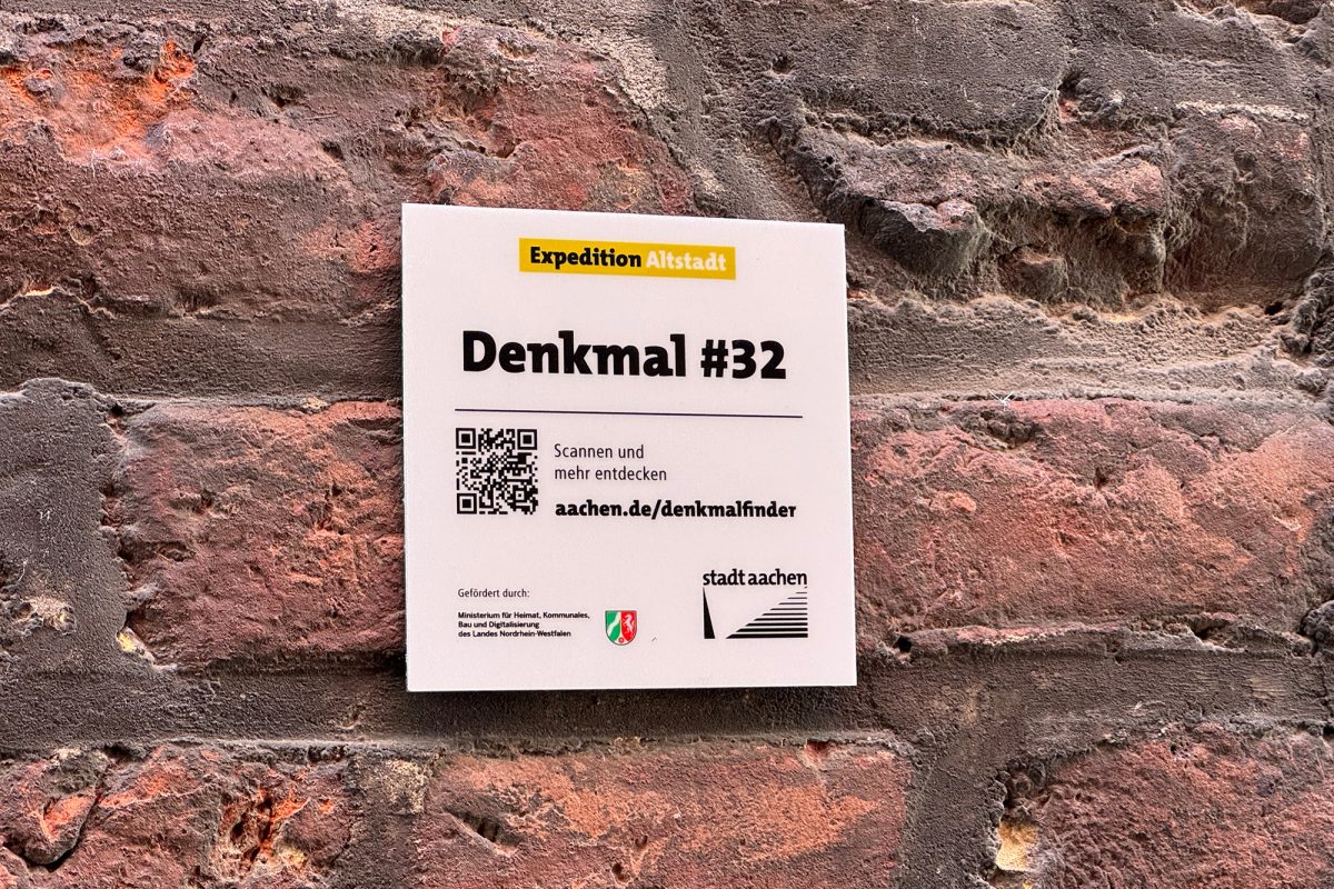 Hinweisschild auf eine historische Fassade mit einem abgedruckten QR-Code