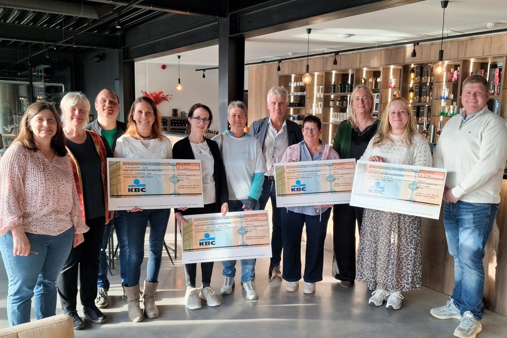 Mitglieder des Verkehrsvereins Raeren sowie mehrerer gemeinnütziger Organisationen posieren mit großen Spendenschecks für ein Gruppenfoto