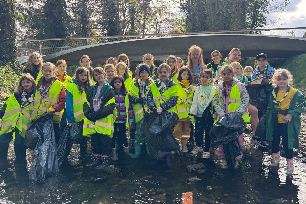 Eine Gruppe Freiwilliger posiert für ein Gruppenbild am Flussufer