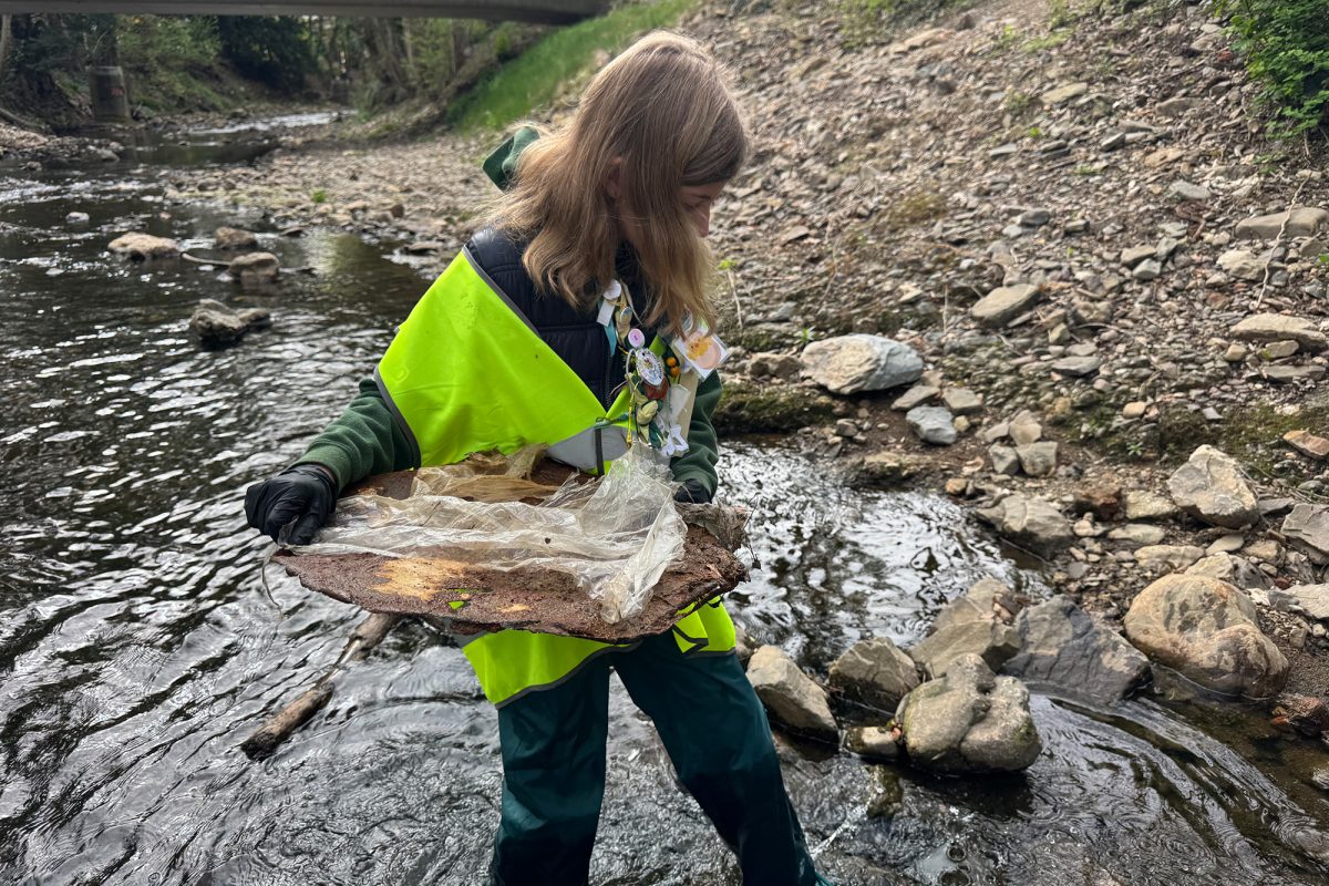 Mädchen beim Müllsammeln am Flussufer