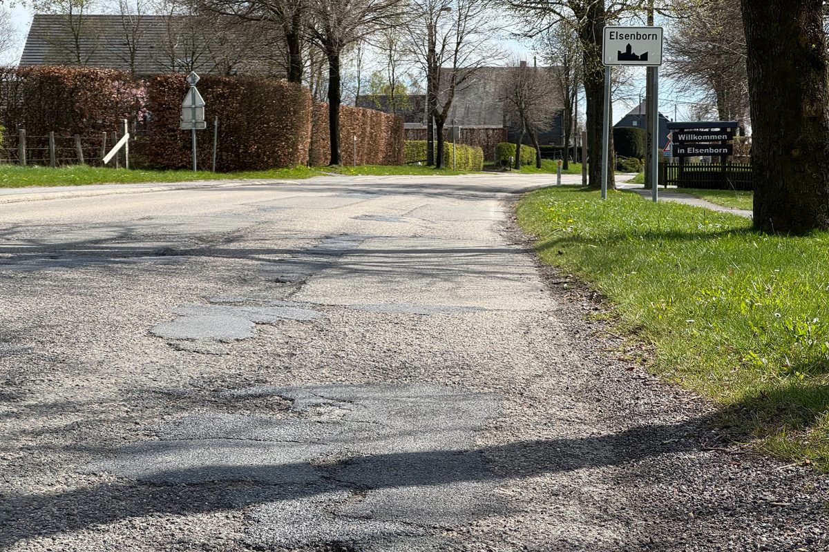 Die Fahrbahn mit Straßenschäden und geflickten Stellen