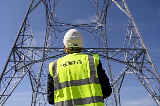 Elia-Mitarbeiter steht vor einem Strommast