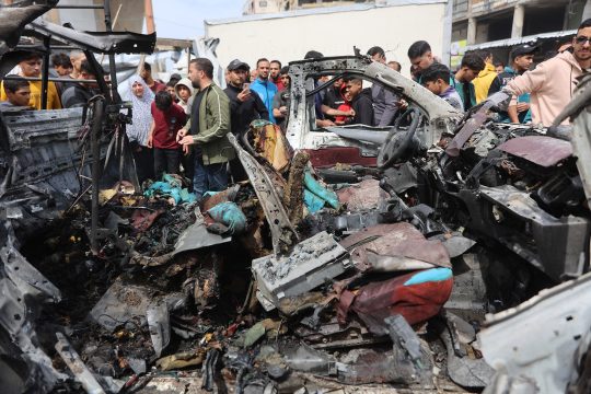 Menschen versammeln sich um ein zerstörtes Auto nach israelischen Angriffen