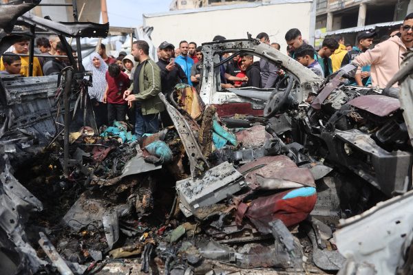 Menschen versammeln sich um ein zerstörtes Auto nach israelischen Angriffen