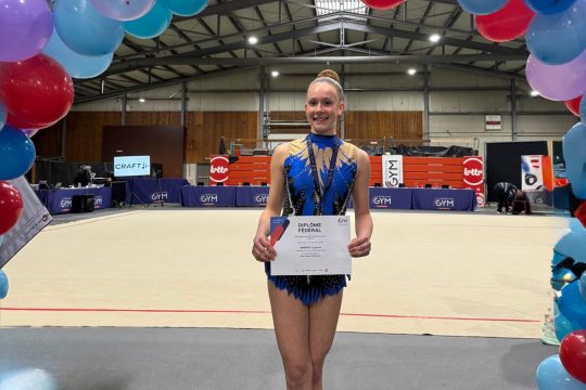 Louanne Arimont hält eine Auszeichnung in der Hand