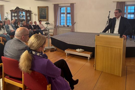 Luc Walpot hält einen Vortrag am Rednerpult vor Publikum