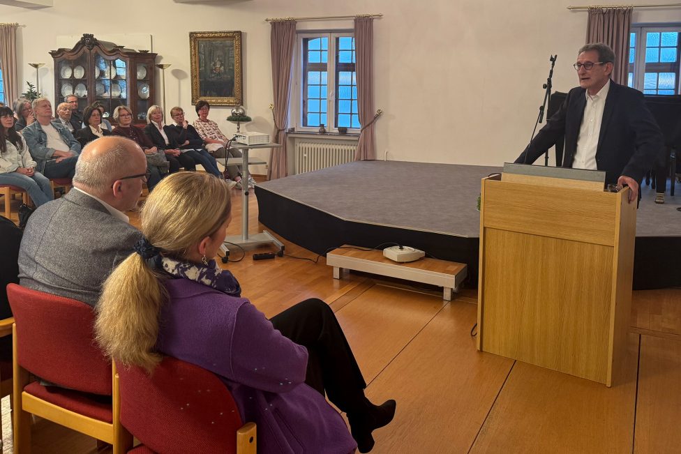 Luc Walpot hält einen Vortrag am Rednerpult vor Publikum