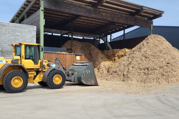 Bagger und Spänehaufen auf dem Betriebsgelände des Unternehmens Peter Müller in Amel-Möderscheid
