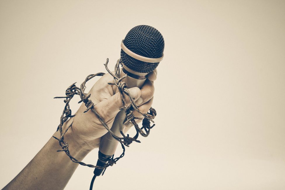 Hand mit Mikro und Stacheldraht