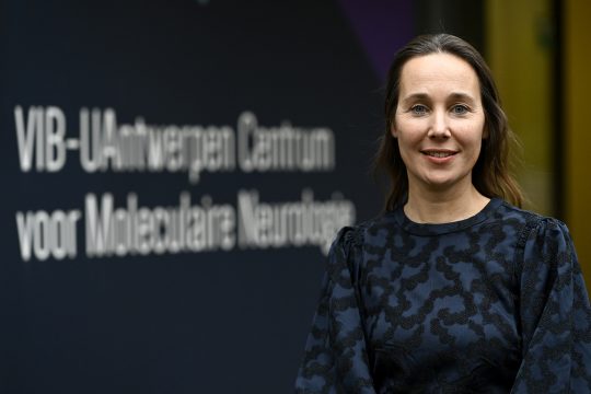 Professorin Rosa Rademakers steht vor einem Schild an einem Gebäude der Universität von Antwerpen